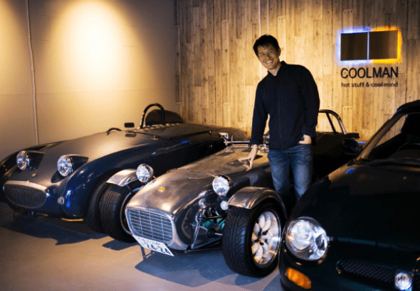 クラシックカーが並んでいるところに人が立っている様子