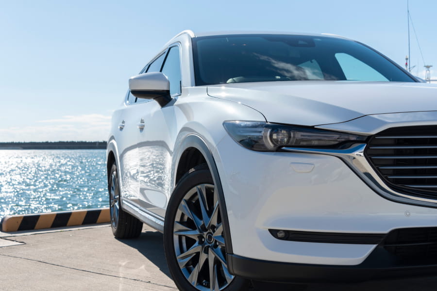 海辺に停められた白いSUVのフロント部分