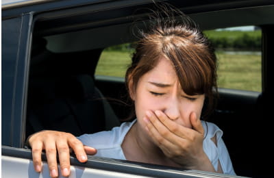 車窓で嘔吐しそうになっている女性の様子